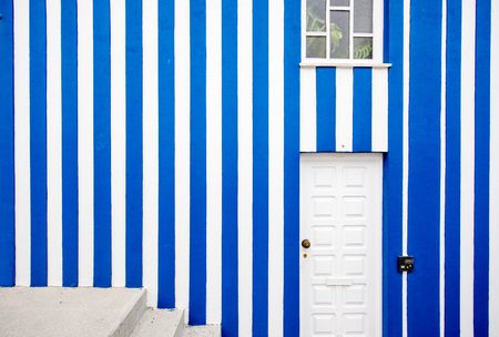 Facade view on the beautiful colorful striped house wall with window, door and stairs for backgroundの写真素材
