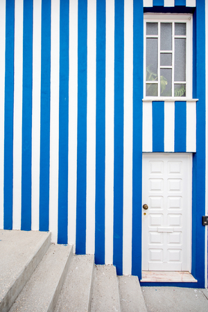 Facade view on the beautiful colorful striped house wall with window, door and stairs for backgroundの写真素材