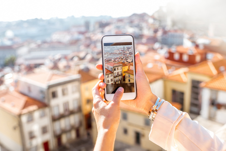 Woman photographing with phone cityscape view on the old town of Porto city in Portugalの写真素材