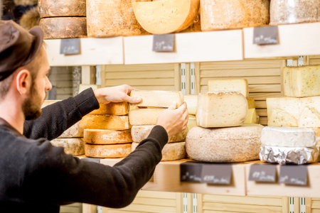 Cheese seller putting goods on the shelves at the cheese store