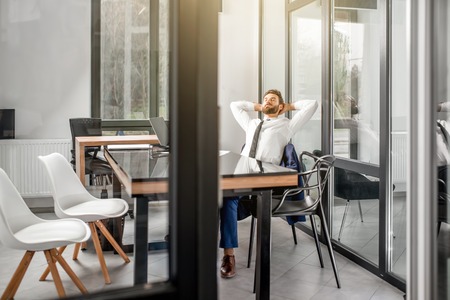 Wide angle view on the office with glass walls and businessman resting on the chairの写真素材