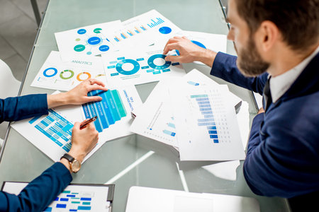 Marketer or analityc manager team working on paper charts at the table. Image focused on the...