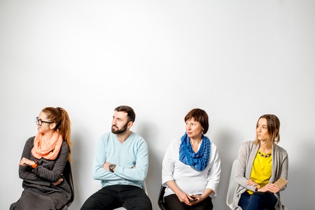 People in casual clothes waiting in a line on the white wall backgroundの写真素材