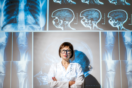 Portrait of a senior woman doctor in uniform with projected x-rays of human partsの写真素材
