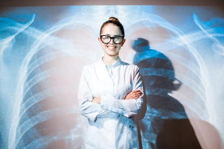 Portrait of a young woman doctor in uniform with projected x-ray of human lungsの写真素材