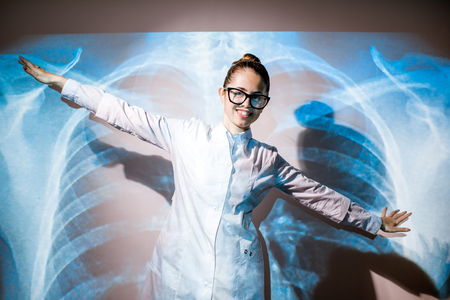 Portrait of a young woman doctor in uniform with projected x-ray of human lungsの写真素材