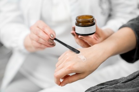 Doctor applying cream on the arm of the young client to try