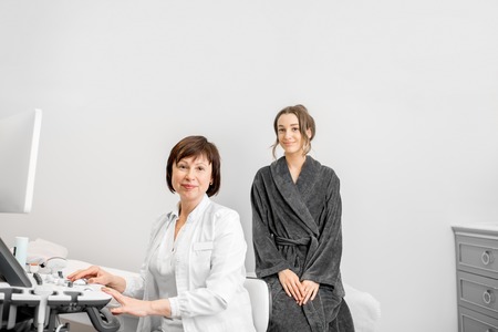 Portrait of a young woman patient with doctor during the consultation after the ultrasound examination in the officeの写真素材