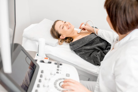 Senior doctor making an ultrasound examination to a young woman patient