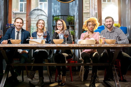 Group of multi ethnic group of business people sitting at the table during the dinner in the modern...