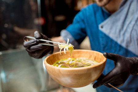 Chief cook decorating a soup with onion in the wooden plateの写真素材