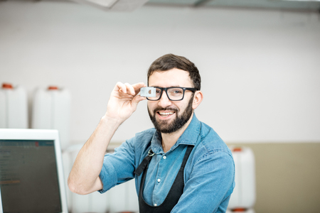 Portrait of a male worker standing with magnifying glass near the operating desk of the printing manufacturingの写真素材