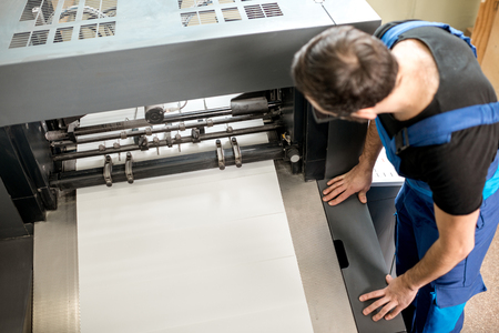 Worker following a printing process on the offset machine at the manufacturingの写真素材