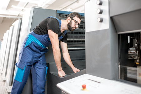 Worker following a printing process on the offset machine at the manufacturingの写真素材