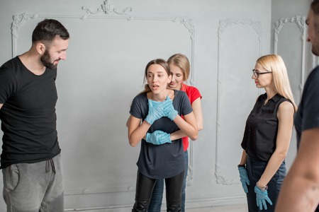 Instructor showing how to safe a life when the human is choked standing during the fisr aid training indoorsの写真素材