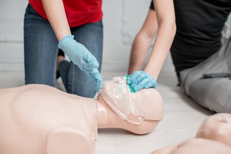 Showing how to throw back dummies head for breathing during the first aid group training indoorsの写真素材