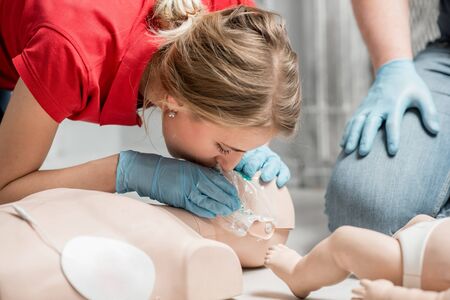 Woman instructor showing how to make artificial respiration with dummy during the first aid training indoorsの写真素材