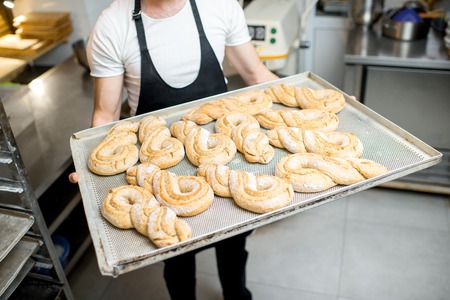 Baker holding a tray with sweet pastry buns at the manufacturingの写真素材
