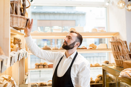 Seller making arrangements on the shelves in the store with bakery products