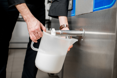 Chef pouring pasteurized milk into the jar for ice cream productionの写真素材