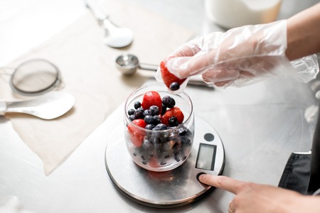 Putting berries into the small jar weighting ingredients for the ice cream productionの写真素材