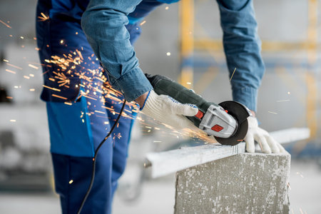 Builder in working uniform cutting metal profile with cutting machine at the construction site...