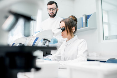 Medics in uniform working with microscope making analysis at the laboratory office