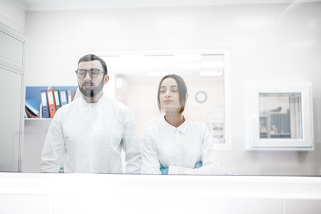 View through the glass on the two medics in uniform standing in the procedural officeの写真素材
