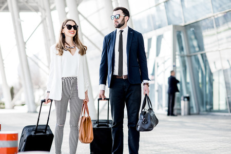 Business couple walking with luggage near the airport during the business tripの写真素材