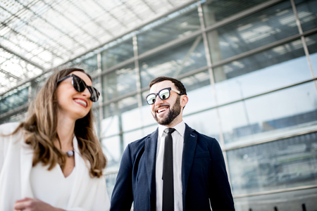 Business woman and man in suits standing near the modern building outdoorsの写真素材