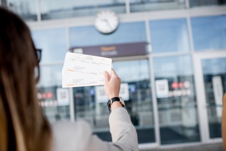 Businesswoman holding tickets in front of the airport entrance outdoorsの写真素材
