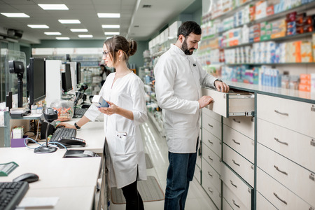 Man and woman pharmacists working at the cash register of the modern pharmacy storeの写真素材