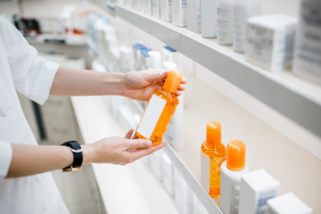 Taking sunscreen lotion from the shelves of the pharmacy store, close-up viewの写真素材