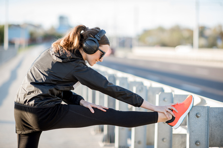 Woman in black sportswear stretching on the bridge during the morning exerciseの写真素材