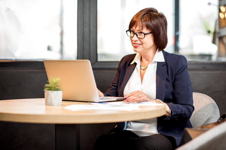 Senior business woman dressed in the suit working with laptop in the modern cafeの写真素材