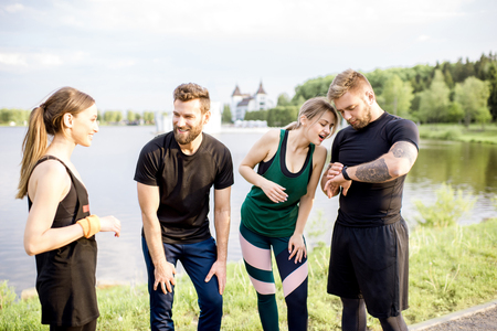 Sports team having fun standing together after the training outdors in the park near the lakeの写真素材