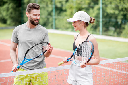 Young couple having fun standing together on the tennis court relaxing after the match outdoorsの写真素材