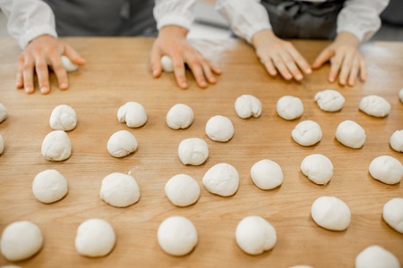 Forming daugh balls for baking buns on the wooden table at the manufacturingの写真素材