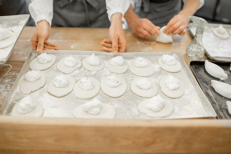 Workers forming raw buns with filling for baking at the manufacturingの写真素材