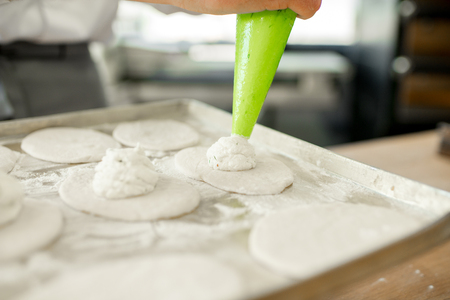 Filling dough workpieces with conefctionery syringe making buns at the manufacturingの写真素材