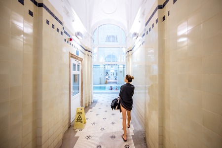 HUNGARY, BUDAPEST - MAY 21, 2018: Interior of the famous Szechenyi medicinal bath with woman walking indoors. This place is the largest bath in Europe with thermal springsのeditorial素材