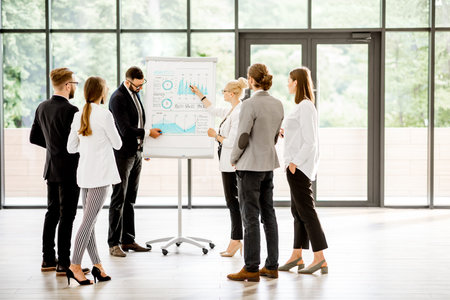 A group of business people standing together during the conference with flip chart at the modern officeの写真素材