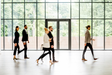 Business people walking at the modern hall on the window background indoors. long exposure image technic with motion blurred peopleの写真素材