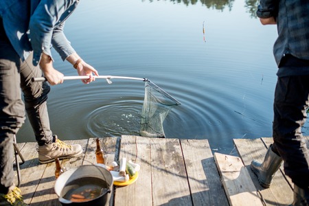 Fishermen catching big fish with fishing net on the lake in the morningの写真素材
