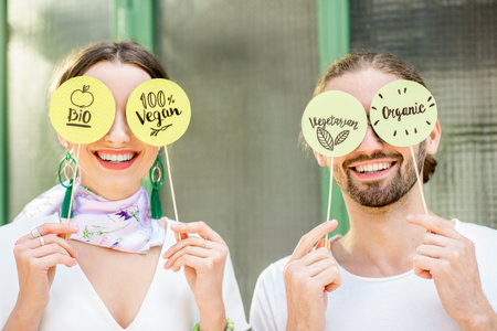 Young couple holding green plates with healthy eating slogans outdoors on the green background