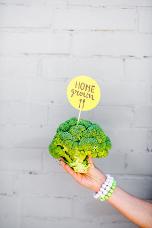 Holding broccoli with green sticker on the gray wall backgroundの写真素材
