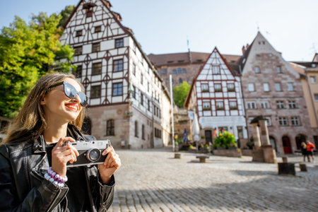 Portrait of a young woman tourist standing on the beautiful city square with old buildings, traveling in Nurnberg, Germanyの写真素材