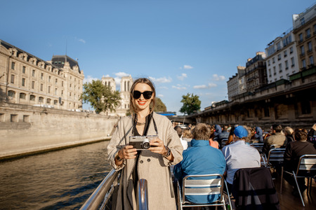 Young woman enjoying beautiful landscape view on the riverside from the tourist ship during the sunset in Parisの写真素材