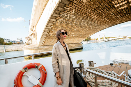 Young woman enjoying beautiful landscape view on the riverside from the tourist ship during the sunset in Parisの写真素材