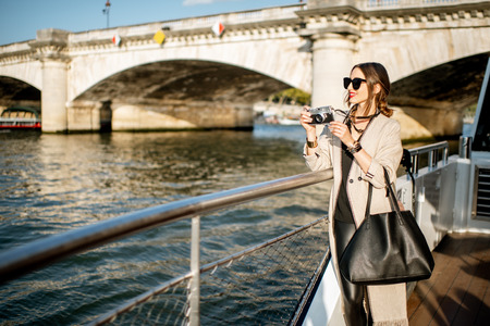 Young woman enjoying beautiful landscape view on the riverside from the tourist ship during the sunset in Parisの写真素材